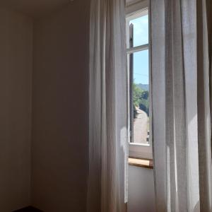 a window with white curtains and a view of a road at Casa Cucun in Saluzzo