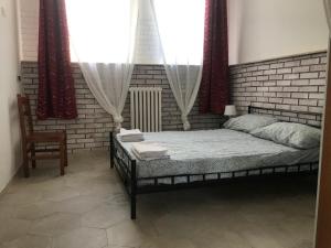 een slaapkamer met een bed, een stoel en ramen bij Lake It Easy Mandello in Mandello del Lario
