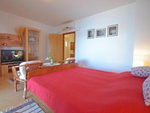 ein Schlafzimmer mit einem roten Bett und ein Wohnzimmer in der Unterkunft Apartment Matal by Interhome in Podorjak