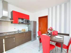 una cocina con armarios rojos y una mesa con sillas rojas en Apartment Aquanur-5 by Interhome, en Sovlje