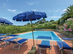 a pool with blue chairs and an umbrella next to it at Holiday Home Casottino - PAA131 by Interhome in Palaia