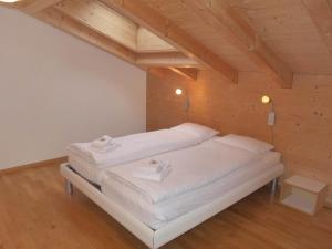 a white bed in a room with a wooden ceiling at Apartment Chalet Almisgässli by Interhome in Grindelwald +21 photos