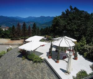 a patio with tables and umbrellas on a mountain at Hotel Mazzoleni in Roncola