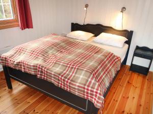 a bed with a checkered blanket and two pillows at Chalet Liaråket by Interhome in Svingvoll +11 photos