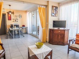 ein Wohnzimmer mit einem TV und einem Tisch in der Unterkunft Apartment Les Glycines by Interhome in Saint Cyprien Plage