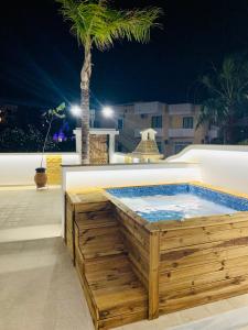 a hot tub in a wooden deck with a palm tree at EROS LUX VILLE 2 in Faliraki