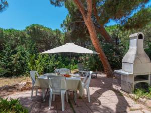 a table and chairs with an umbrella and a fireplace at Apartment Alloggio B by Interhome in La Ciaccia