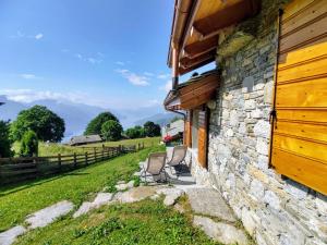 dwa krzesła siedzące przed kamiennym budynkiem w obiekcie Holiday Home Il Nido d'Aquila - GRV635 by Interhome w mieście Livo