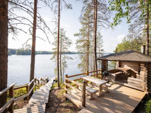 a wooden deck with a gazebo next to a lake at Holiday Home Kalliomökki by Interhome in Huuhanaho