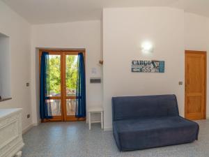 a living room with a blue chair and a door at Holiday Home Trebbiano by Interhome in Greuli  +23 photos
