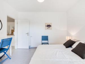 ein weißes Schlafzimmer mit einem Bett und einem blauen Stuhl in der Unterkunft Apartment les Terrasses de Capbreton-2 by Interhome in Capbreton