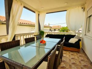 a dining room with a glass table and a couch at Apartment Amadea-1 by Interhome in Obrovac