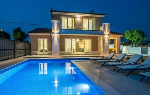 a villa with a swimming pool in front of a house at Villa Periska in Krk