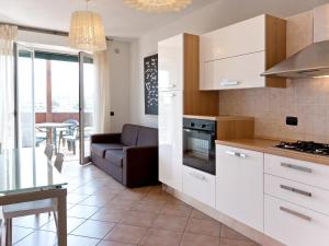 a kitchen with white cabinets and a couch and a table at Apartment Comfort-3 by Interhome in San Vincenzo