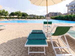 a beach chair and an umbrella next to a swimming pool at Apartment Comfort-3 by Interhome in San Vincenzo