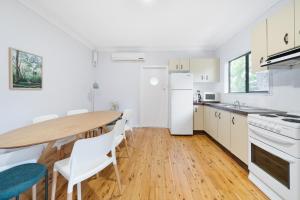 a kitchen with a wooden table and white appliances at Beach Shack semi detached, 2 Min Walk to Beach-Lilly Pilly in Pearl Beach