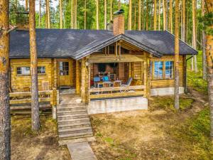une cabane en rondins dans les bois avec une terrasse couverte et des escaliers dans l'établissement Holiday Home Villa kukkapää by Interhome, à Sulkava