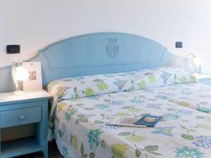 a bed with a blue headboard with a book on it at Apartment Santa Costanza-1 by Interhome in San Vincenzo +19 photos