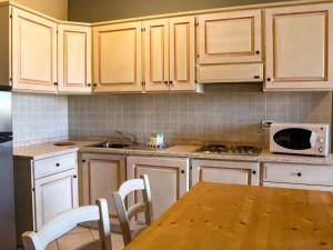 cocina con armarios de madera, mesa y microondas en Apartment Santa Costanza-4 by Interhome, en San Vincenzo