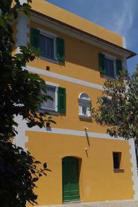 a yellow house with green shutters and a window at Apartment Casa del Poggio by Interhome in Brasi
