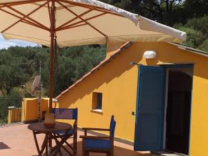 una casa gialla con tavolo e ombrellone di Apartment Casa del Poggio by Interhome a Brasi