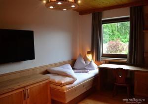 a room with a bed with a desk and a television at Glückchalet in Rettenschöss