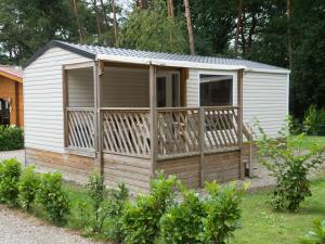 a cabin with a deck in a yard at Holiday Home De Brenkberg-1 in Schinveld