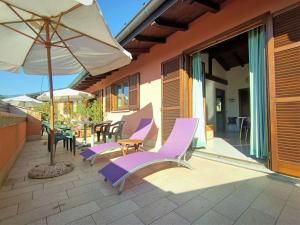 a patio with purple chairs and an umbrella at Apartment Residenza Agrifoglio-7 by Interhome in Luino