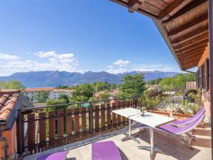 a balcony with a white table and purple chairs at Apartment Residenza Agrifoglio-8 by Interhome in Luino
