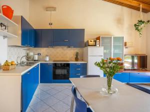 a kitchen with blue cabinets and a table with a vase of flowers at Apartment Residenza Agrifoglio-8 by Interhome in Luino +30 photos