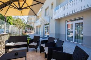 a patio with chairs and tables and an umbrella at Hotel Baby in Rimini