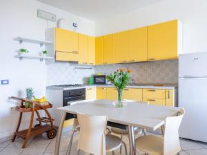 a kitchen with yellow cabinets and a table with a vase of flowers at Apartment Residenza Agrifoglio-10 by Interhome in Luino +23 photos