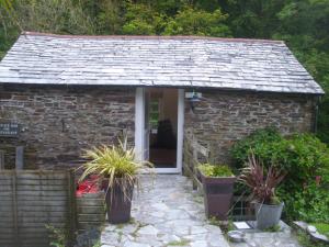 a small stone cottage with potted plants in front of it at The Mill House in Tintagel