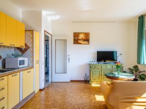 a kitchen with yellow cabinets and a table with a microwave at Apartment Residenza Agrifoglio-13 by Interhome in Luino +32 photos