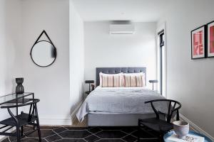 a bedroom with a bed with a mirror and a chair at Richmond Studios in Melbourne