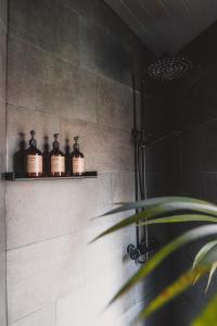 Baño con 3 botellas en un estante en una ducha en Hekso treehouse 