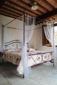 カーゾレ・デルザにあるAlla Pieveのベッドルーム(白いカーテン付きの天蓋付きベッド1台付)