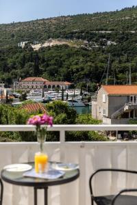 uma mesa com um vaso de flores numa varanda em Apartments Silvija em Mokošica