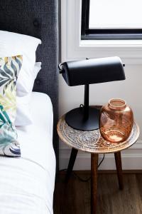 a black lamp on a table next to a bed at Richmond Studios in Melbourne