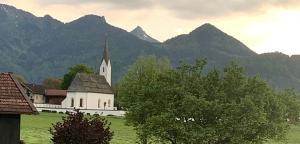 a church in a field with mountains in the background at alpenkind in Staudach-Egerndach
