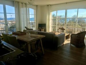 a living room with a couch and a table and windows at Port Rive Gauche Roseliere in Marseillan
