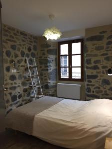 a bedroom with a bed and a stone wall at Hôtel Restaurant Le Bardière in Laguiole