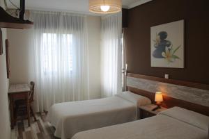 Habitación de hotel con 2 camas y ventana en La Flor de Quejo en Isla