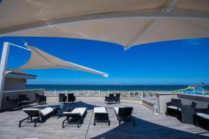 a patio with chairs and tables and a view of the ocean at Hotel Baby in Rimini