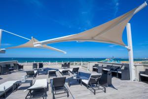 a patio with chairs and tables and the beach at Hotel Baby in Rimini