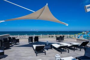 a large white umbrella over a patio with the beach at Hotel Baby in Rimini