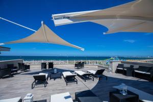 a patio with chairs and umbrellas and the ocean at Hotel Baby in Rimini