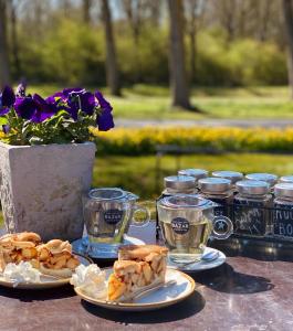 een tafel met borden eten en kopjes thee bij Hotel Molengroet in Noord-Scharwoude