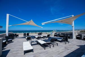 a patio with chairs and umbrellas on the beach at Hotel Baby in Rimini