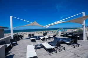 a patio with chairs and tables and the beach at Hotel Baby in Rimini